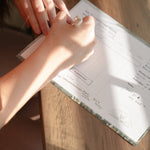 woman writing on sacramental calendar with brown pen on wooden table