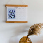 zoomed out photo of liturgical calendar next to brown glass vase and candle 