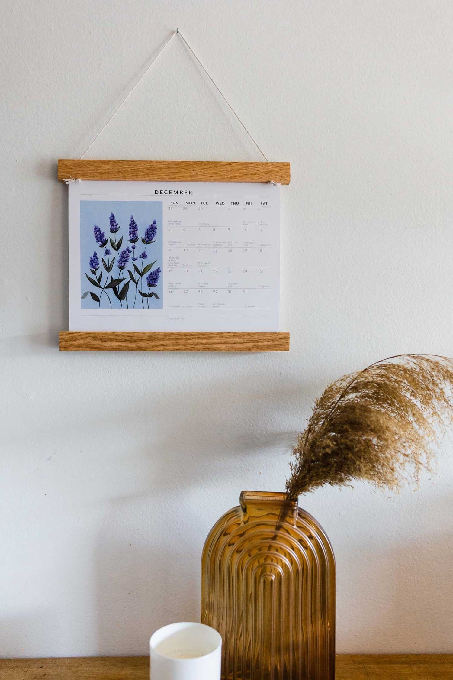 zoomed out photo of liturgical calendar next to brown glass vase and candle 