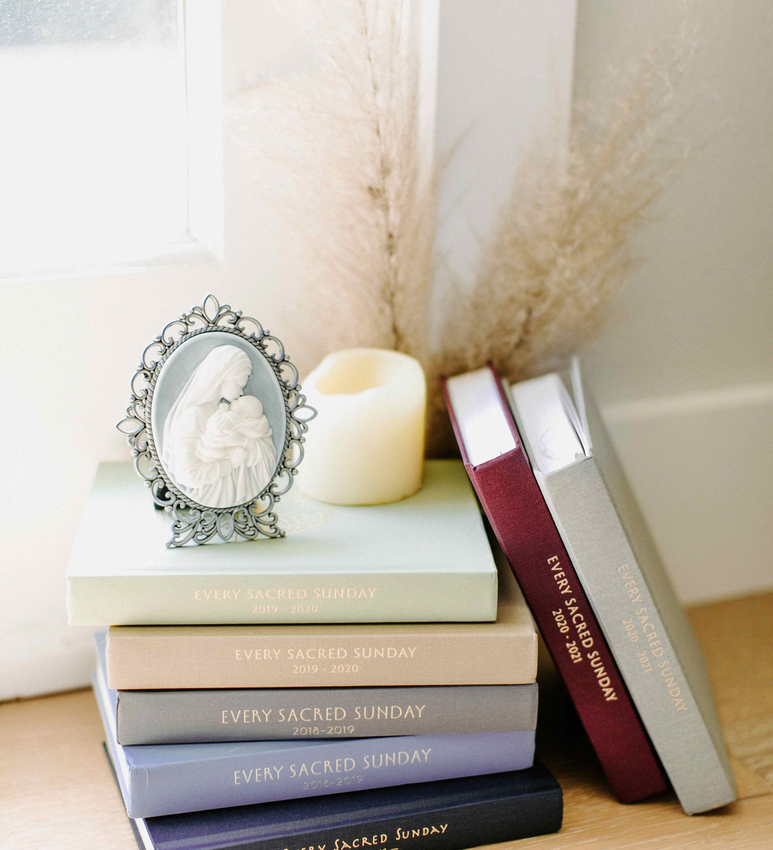 mass journals in stack next to window with candle and mother's kiss cameo