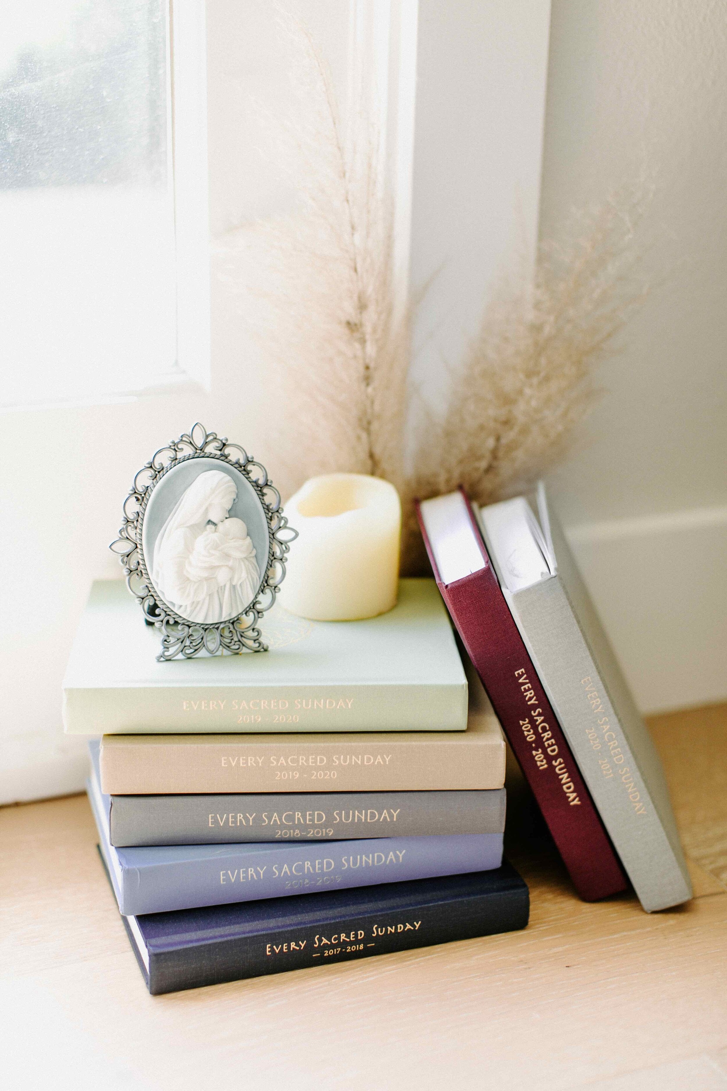 mass journals in stack next to window with candle and mother's kiss cameo